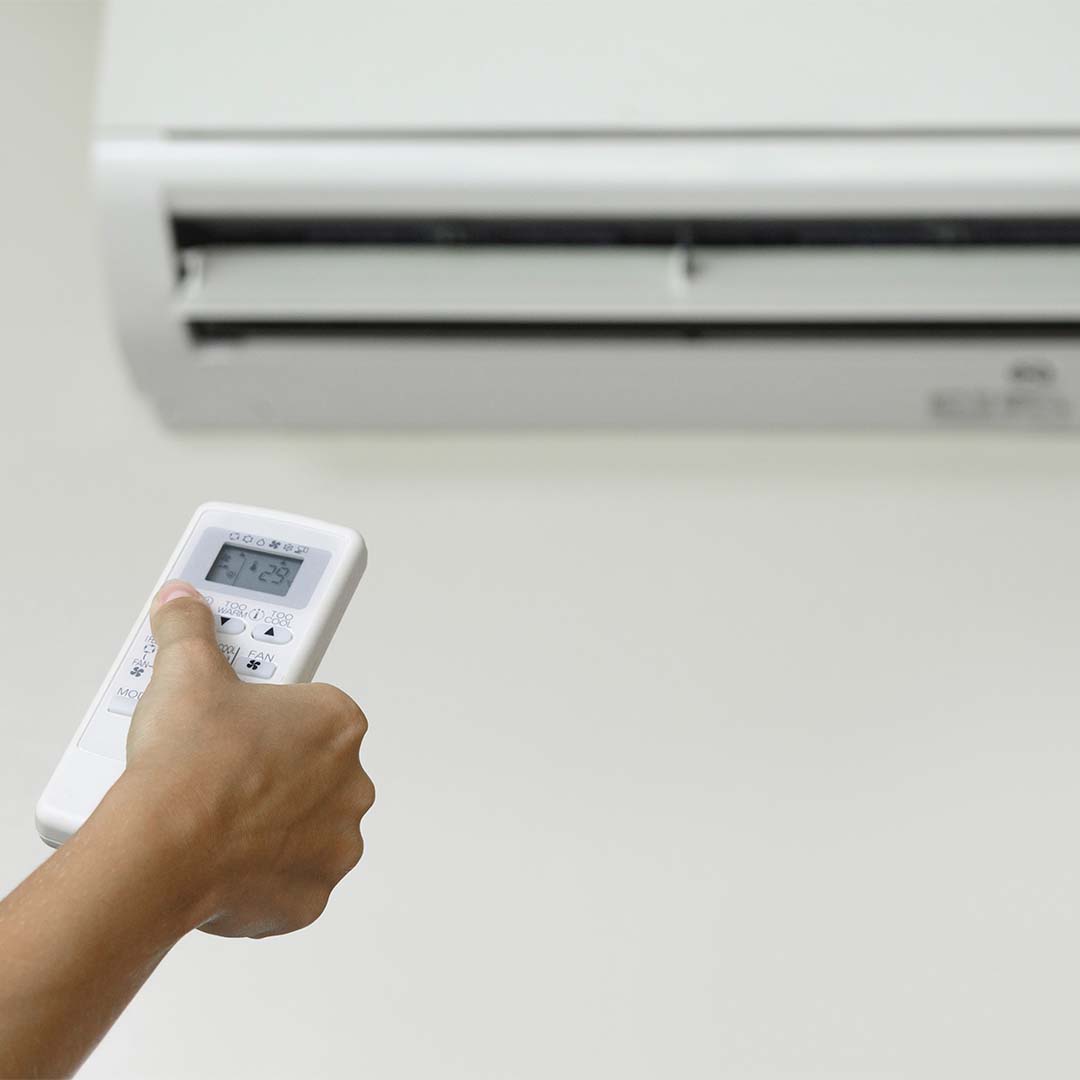 Person changes temperature on AC unit with remote
